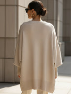 Oversized poncho sweater, back view with ribbed hem, light beige