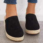 Black slip-on closed-toe wedge mules with textured jute platform and low heel.