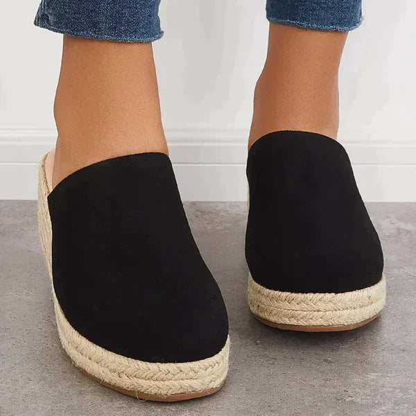 Black slip-on closed-toe wedge mules with textured jute platform and low heel.
