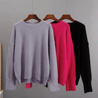 Crewneck cashmere sweaters on hangers: light gray, fuchsia, and black.