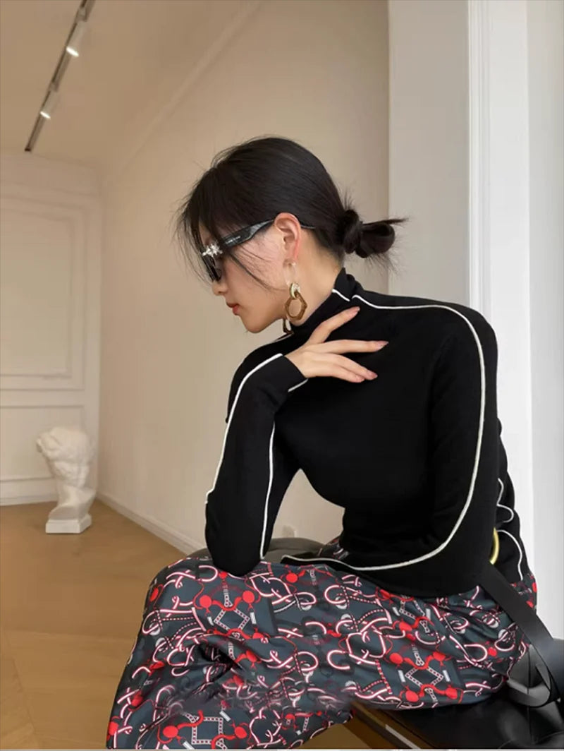 Black fitted turtleneck top with white piped seams and long sleeves
