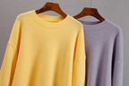 Yellow cashmere crewneck sweater with long sleeves; lavender sweater beside it.