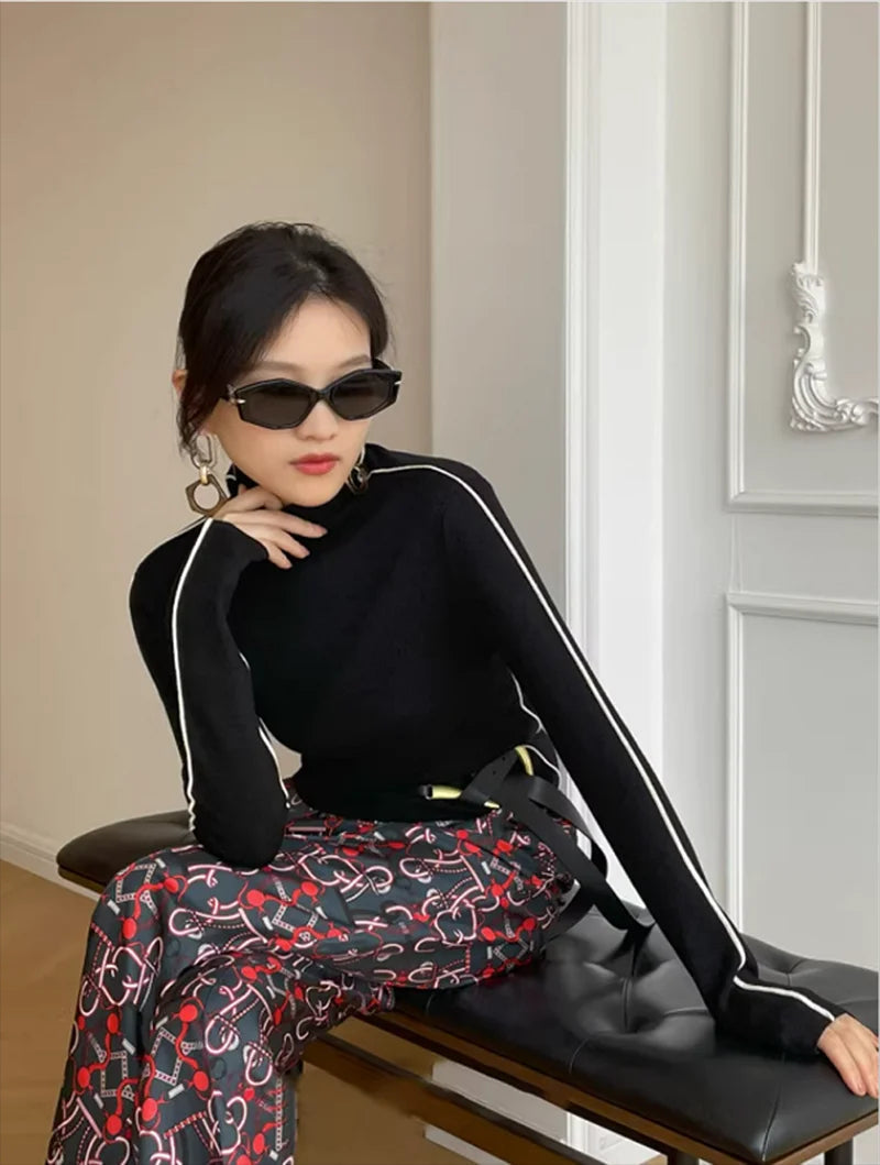 Black long-sleeve turtleneck top with white contrast piping along the arms