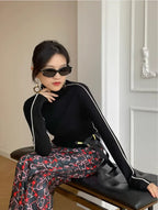 Black long-sleeve turtleneck top with white contrast piping along the arms