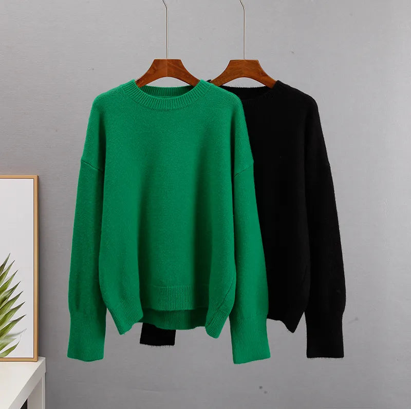 Cashmere crewneck sweaters on hangers: green and black, ribbed collar and cuffs.