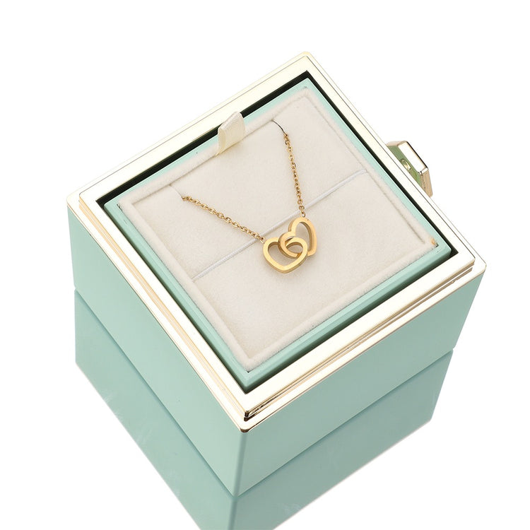 Teal jewelry gift box with gold heart pendant necklace on white display pillow