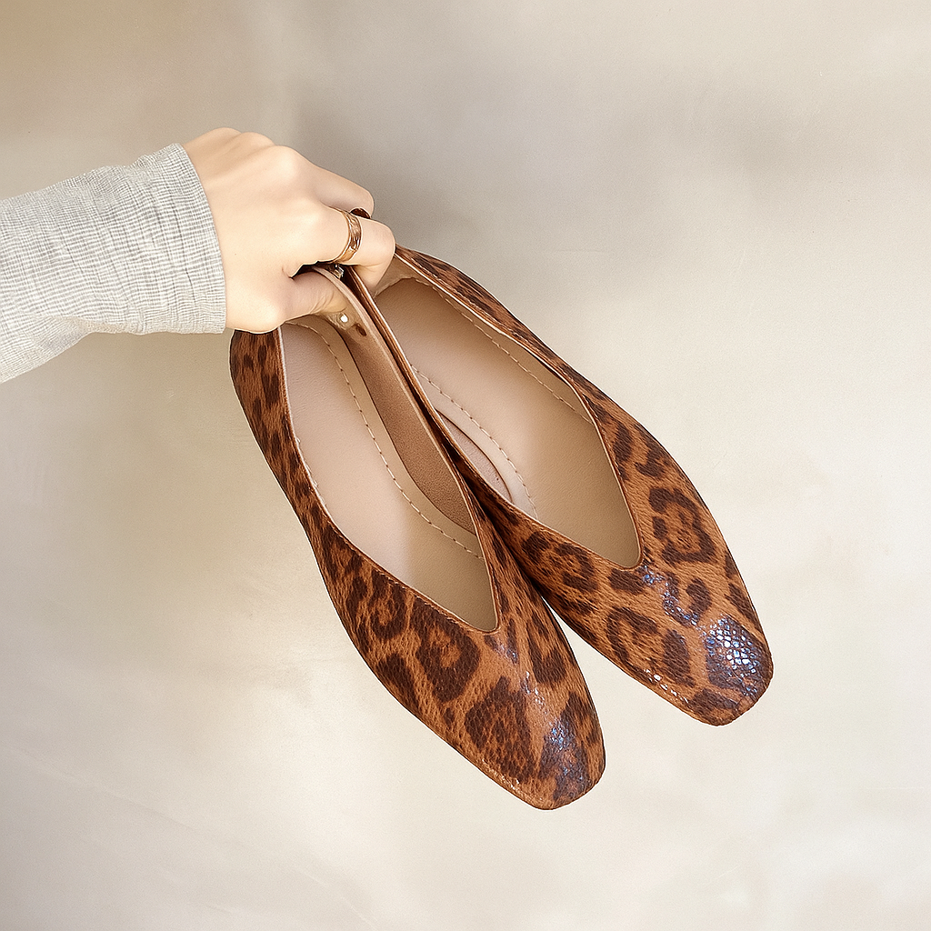 Leopard print slip-on loafers held by hand, rounded toe and stitched interior