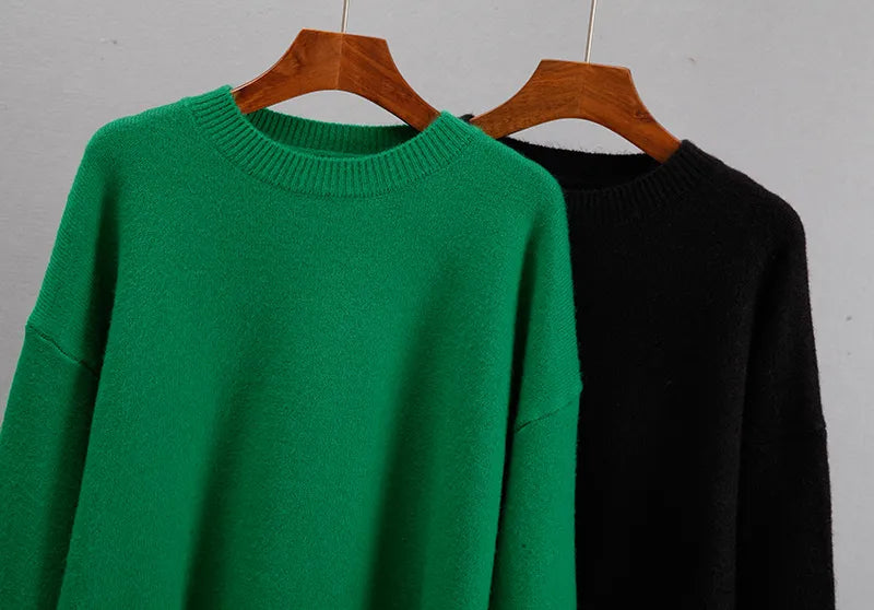 Green cashmere crewneck sweater on hanger with ribbed collar; black beside it.