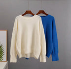 Cream cashmere crewneck sweater and blue crewneck sweater on hangers.