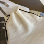 Cream turtleneck knit with black contrast edging at the collar opening