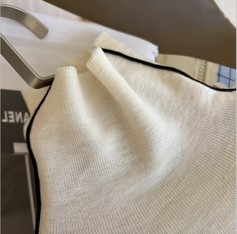 Cream turtleneck knit with black contrast edging at the collar opening