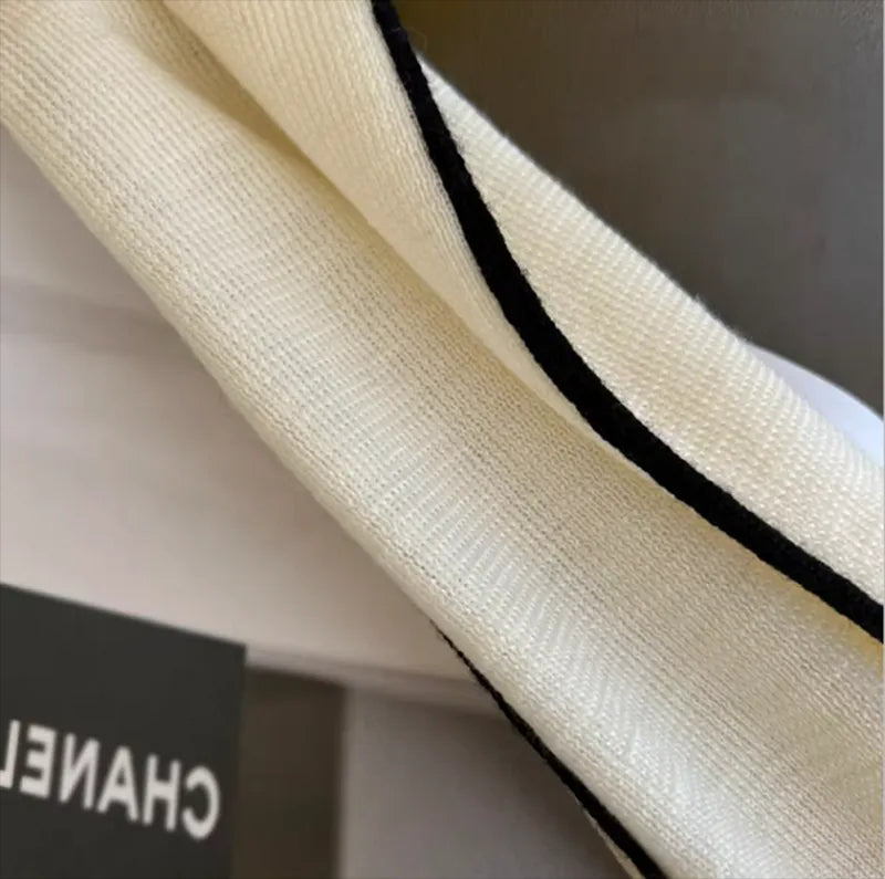 Cream turtleneck sleeve with black contrast trim along the inner edge