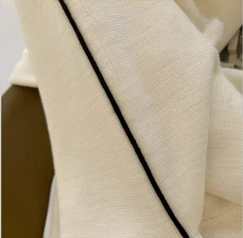 Cream knit turtleneck with black contrast piping along the neckline seam