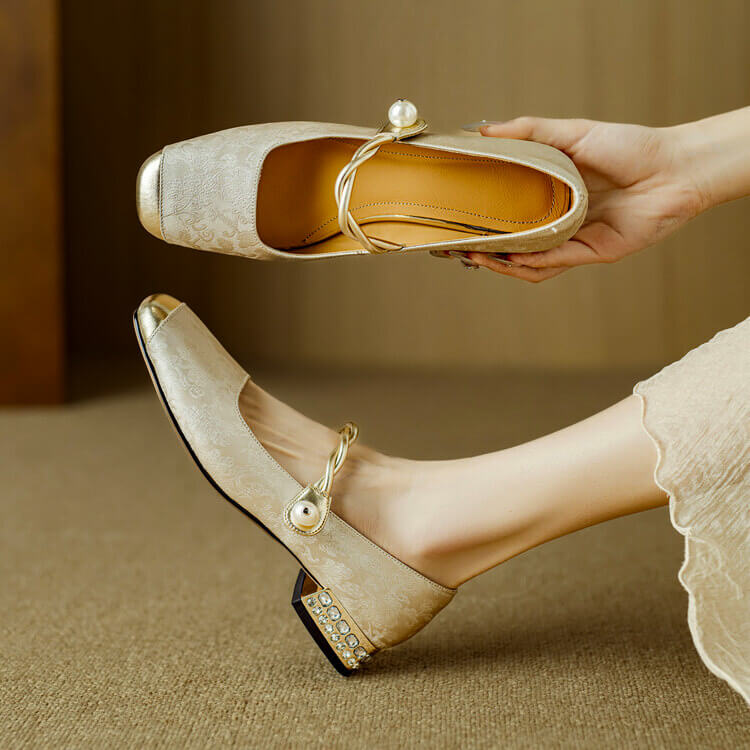 White Mary Jane flat shoes with twisted strap, pearl button detail, and low block heel