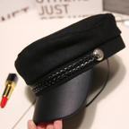 Black peaked cap top and brim close-up with braided trim and round metal button