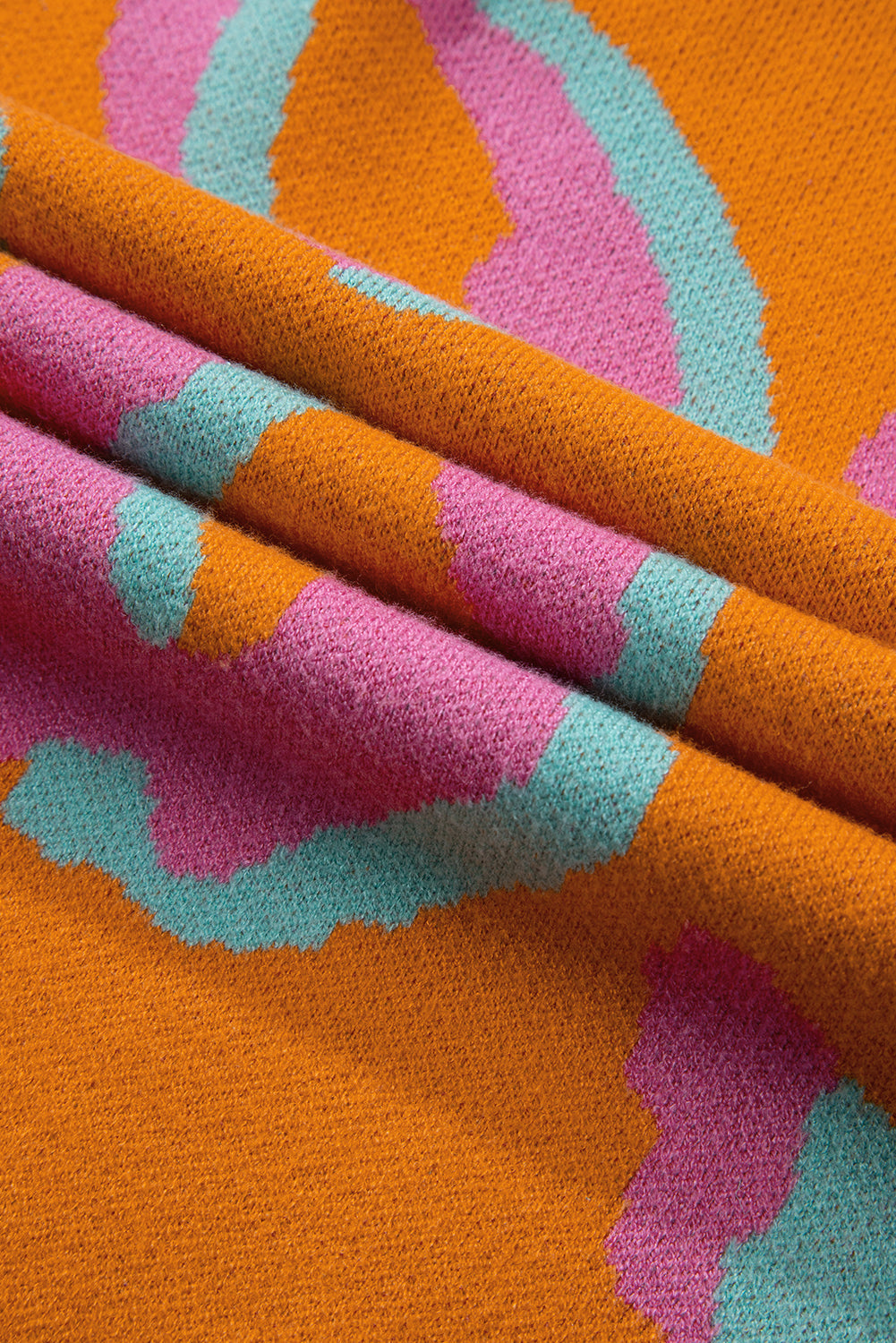 Close-up of orange, pink, and teal leopard-style knitted fabric texture.