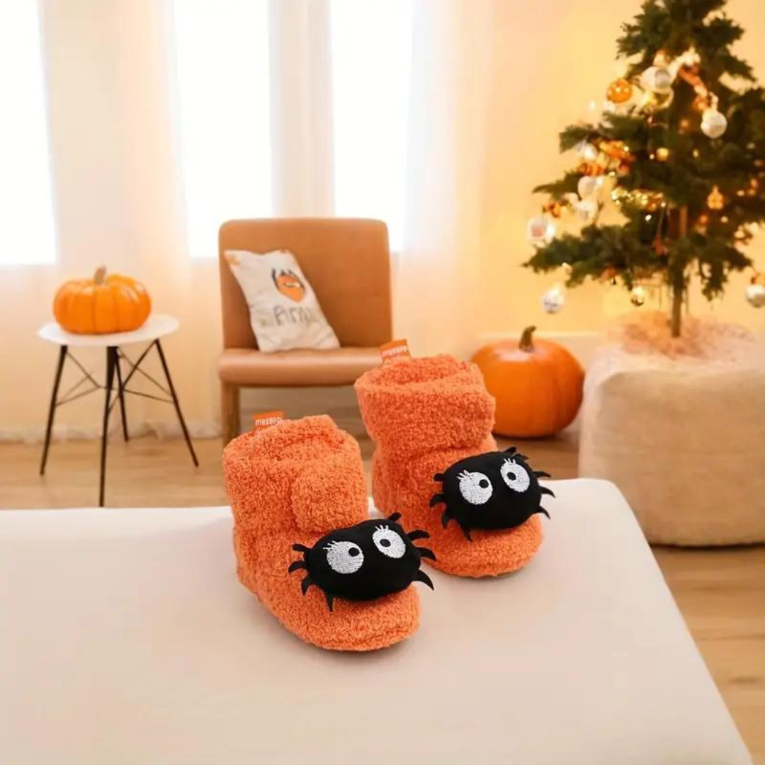 Children's Halloween slippers in orange with black spider-like cartoon eyes and web details