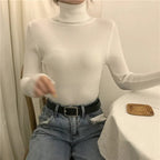Cream ribbed turtleneck sweater with long sleeves and a high neckline.