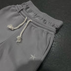Unisex light gray joggers with elastic waist, drawstring ties, and embroidered star