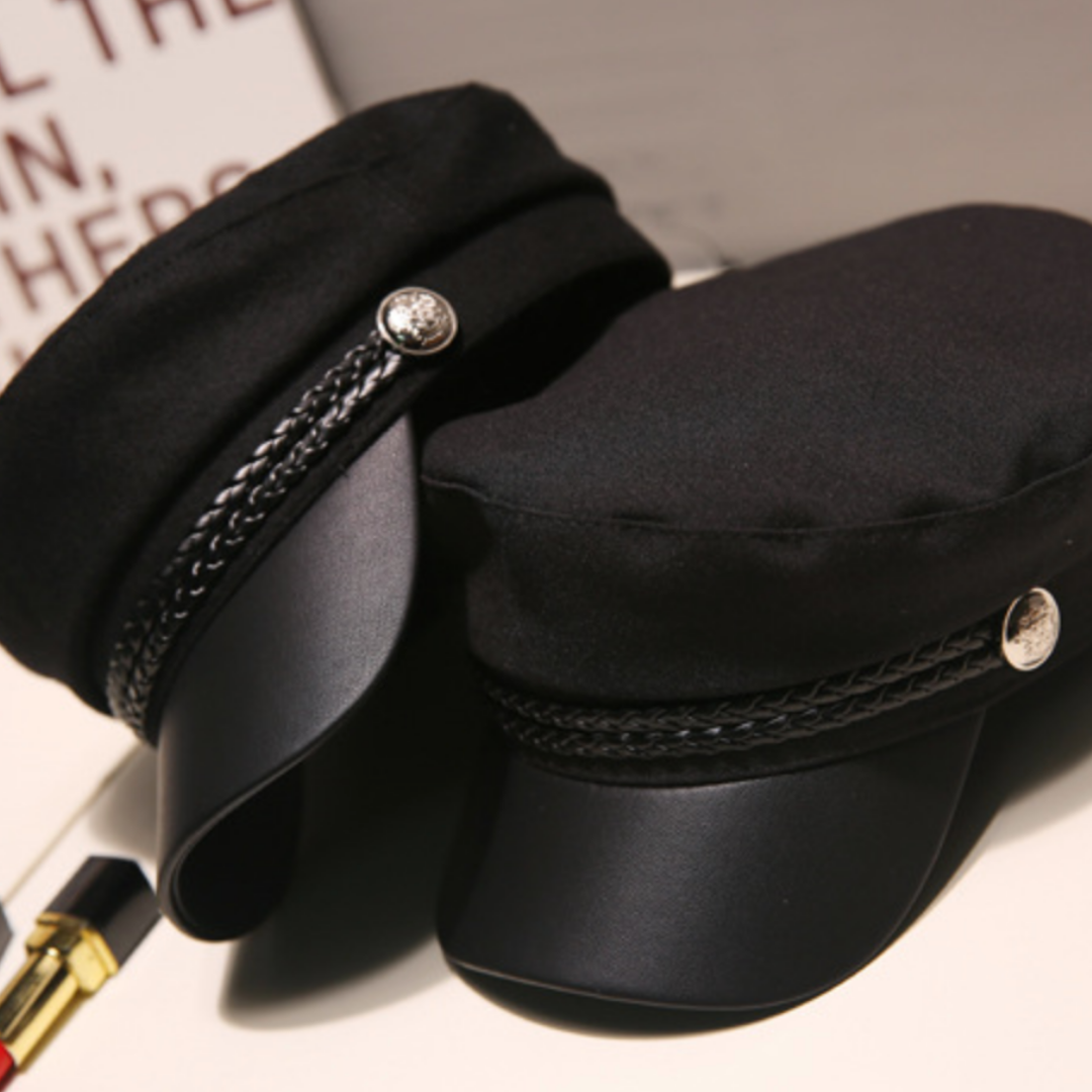 Black military-style cap side view with braided cord and round metal button
