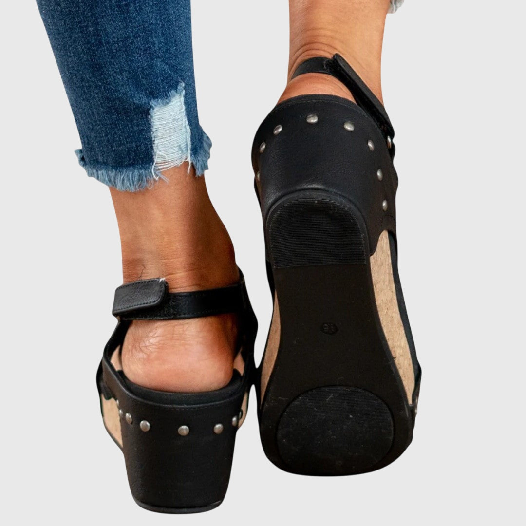 Black cushioned wedge sandals with perforated side straps and a padded heel platform.