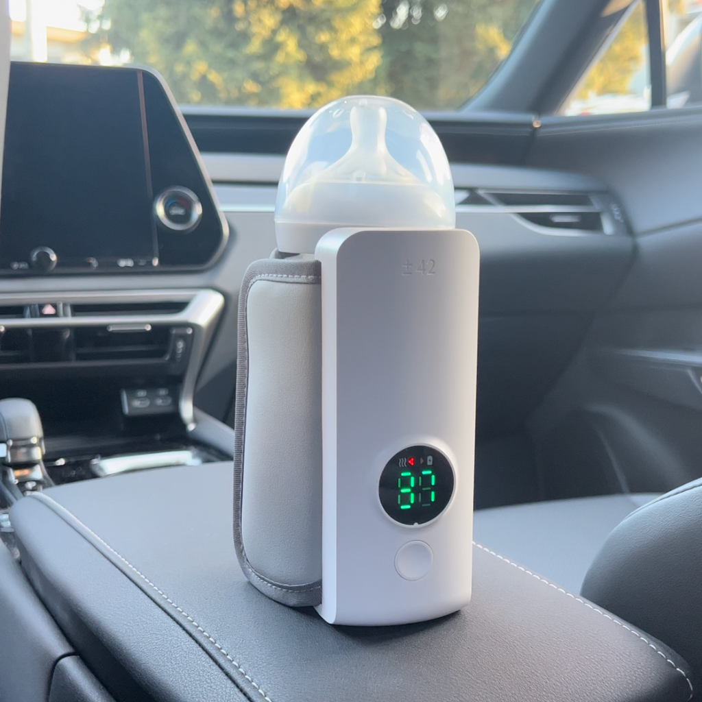 Rechargeable portable bottle warmer with white cover and green LED display, in car seat