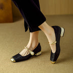 Black Mary Jane flat shoes with twisted strap, pearl button detail, and low block heel