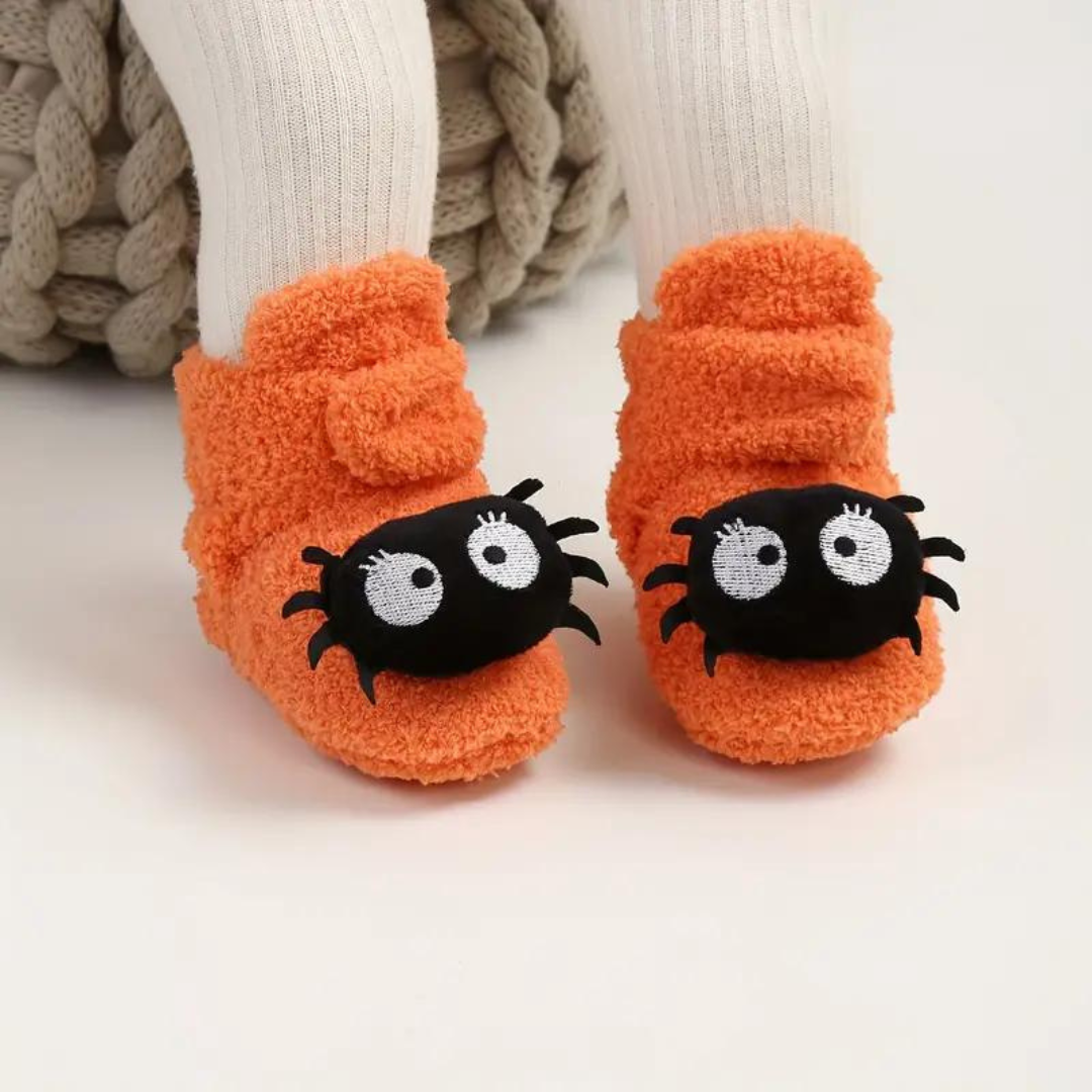 Children's Halloween slippers in orange with black spider-like cartoon face eyes