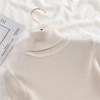 Ribbed turtleneck sweater in off-white/cream, close-up of layered mock neck