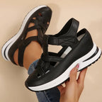 Black platform sandals with cross strap design and cushioned sole, close side view