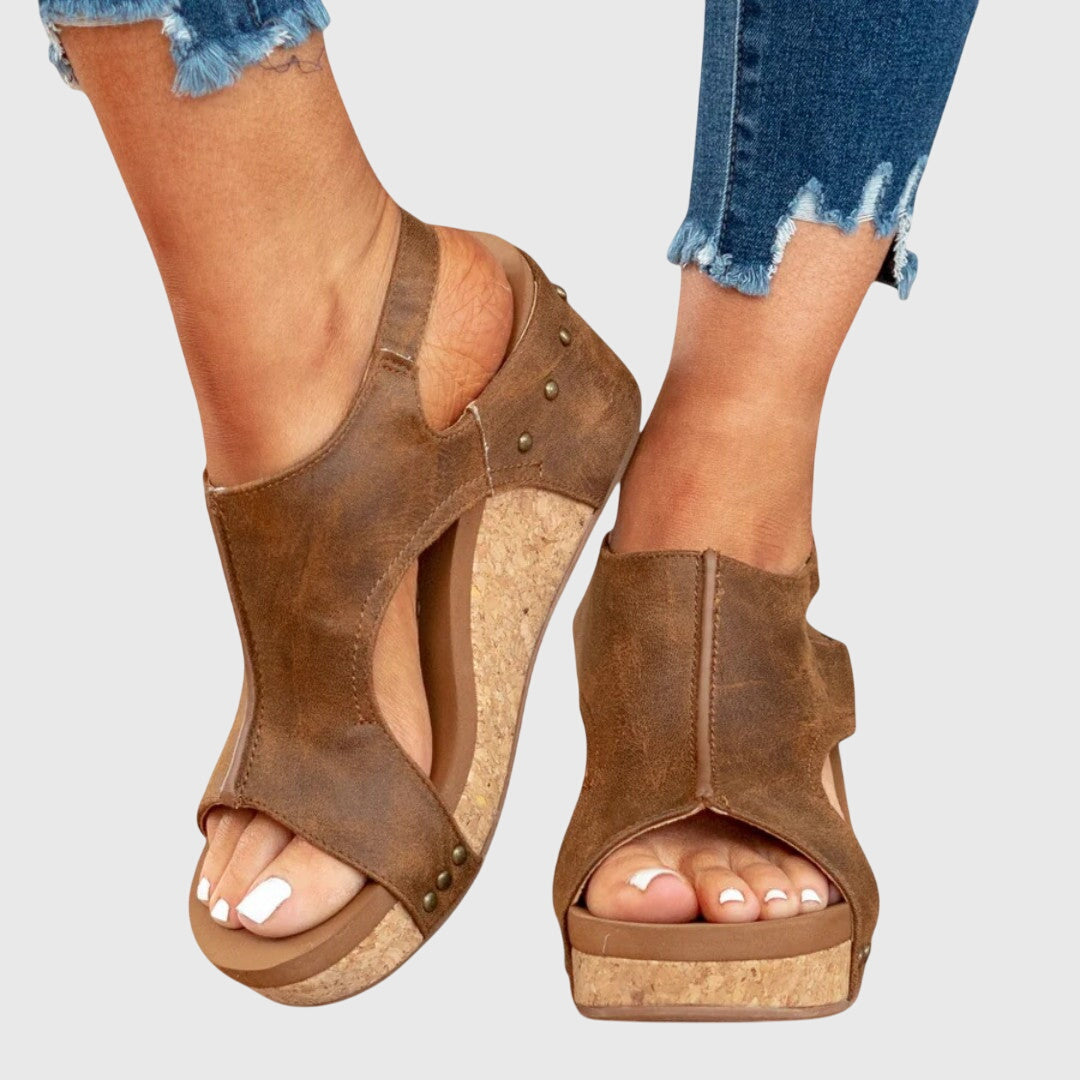 Brown suede wedge sandals with open toe, ankle strap, and stud trim on the sides.