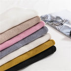 Ribbed turtleneck sweater stack in white, pink, gray, mustard, and black hues.