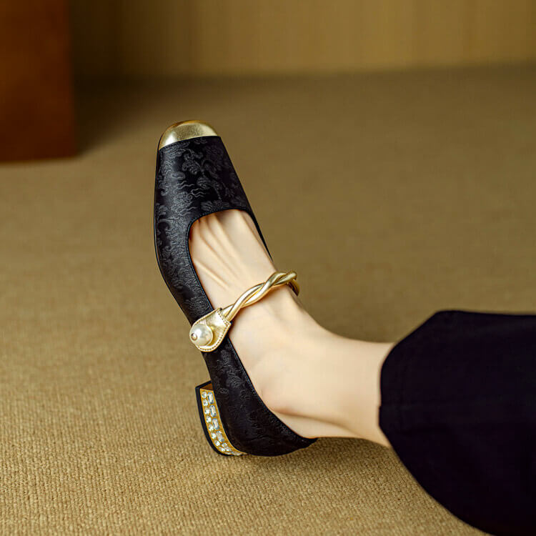 Black Mary Jane flat shoes with twisted strap, pearl button detail, and decorative heel trim