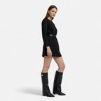 Black knee-high suede boots with buckle strap and pointed toe, low heel