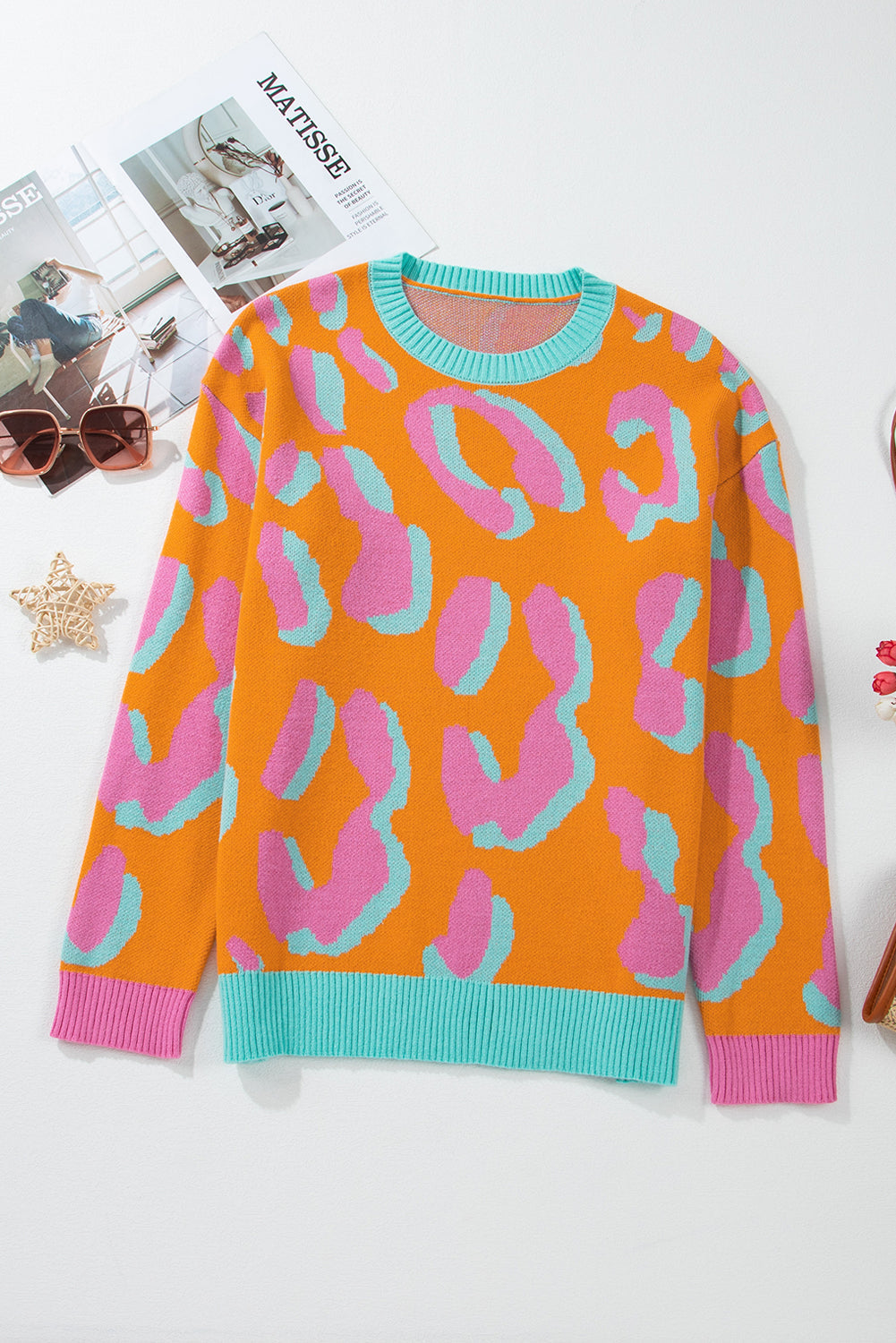 Women’s front view sweater with orange, pink, and teal leopard-style print; round ribbed collar.