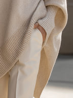 Ribbed knit cuff and hem detail on oversized poncho sweater, light beige