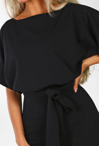 Black high-waist jumpsuit close-up with gathered drape top and bow-tied waist