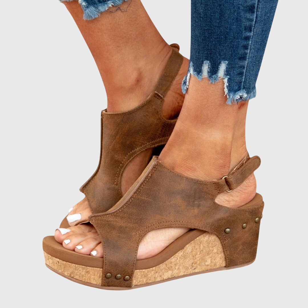 Brown wedge sandals with side cutouts, ankle strap, and stud accents on the wedge.