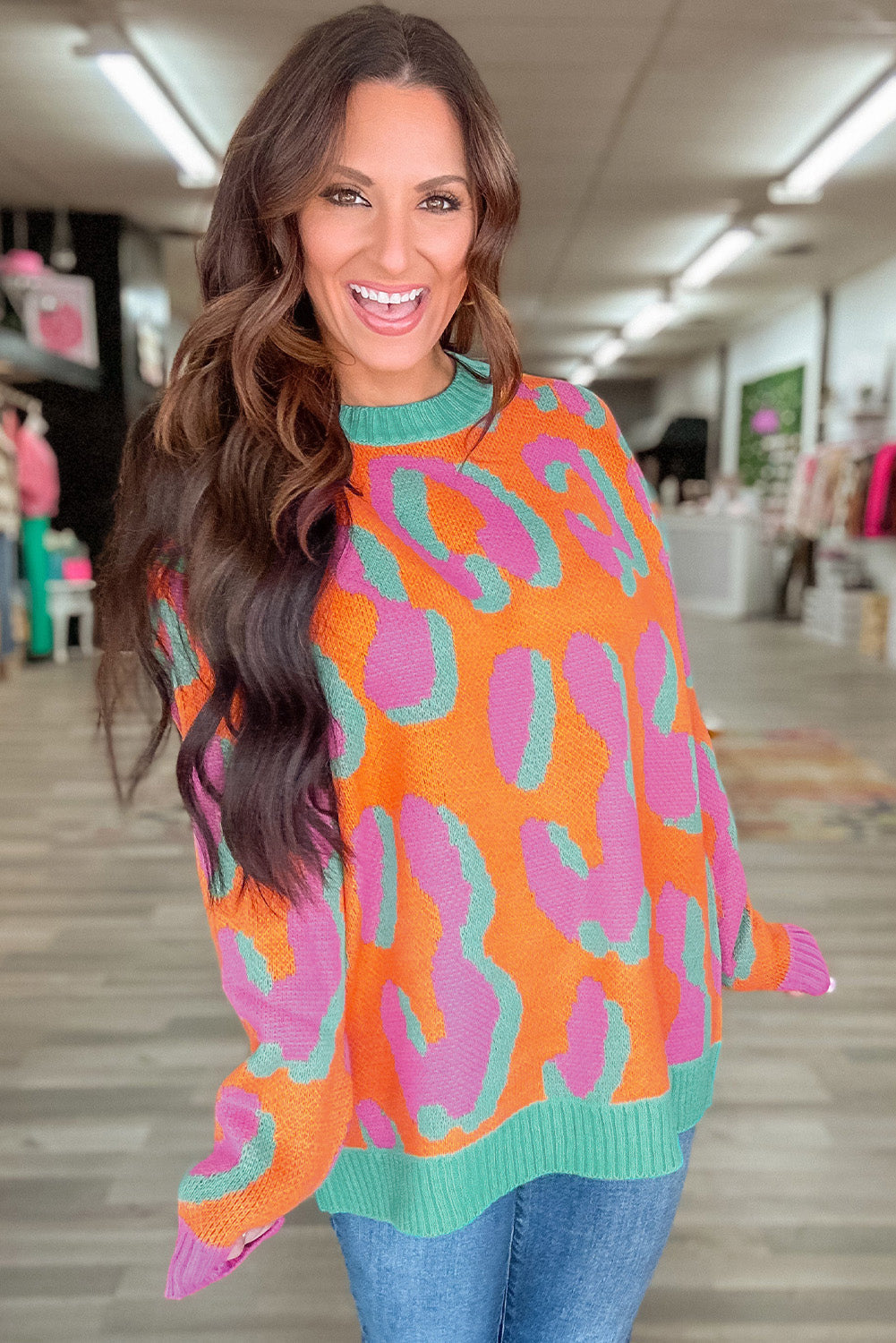 Women’s sweater in orange, pink, and teal leopard-style print; long sleeves, ribbed cuffs.