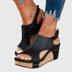 Black cushioned wedge sandals with open toe, ankle strap, and side stud accents.