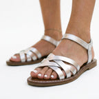 White flat strappy sandals with crisscross straps and buckled ankle strap