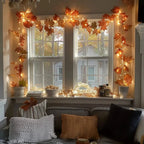 orange maple leaf garland with warm string lights across window wall