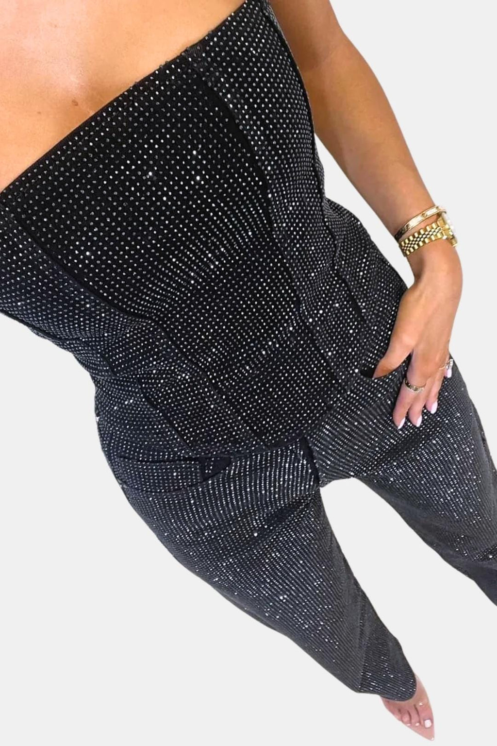 Black strapless glitter jumpsuit close-up: ruched waist seams and patch pockets