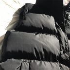 Dark gray quilted puffer bodywarmer with high neck and front zipper, padded shoulders