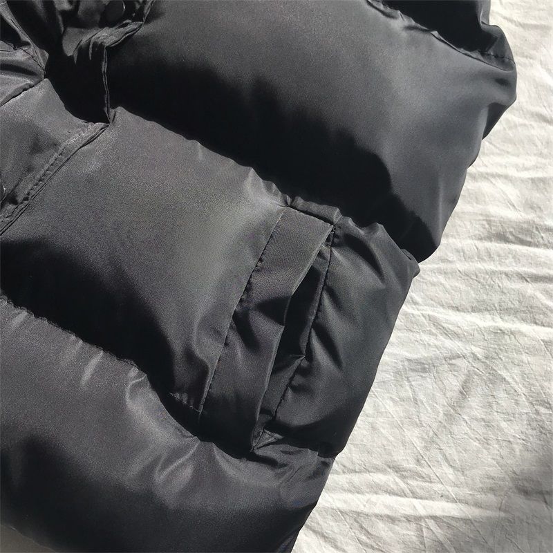 Dark gray puffer bodywarmer close-up with stitched paneling and gathered waist hem