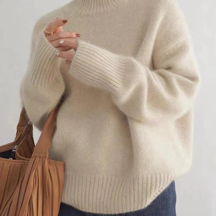 Beige cashmere turtleneck sweater close-up: ribbed cuffs, collar, and relaxed knit drape.