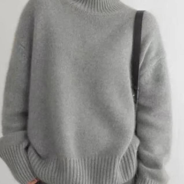 Gray cashmere turtleneck sweater close-up with ribbed hem and long sleeves.