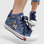Blue denim high-top sneaker with lace-up front and metal charm detail on the side