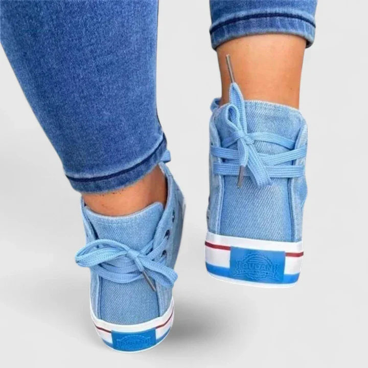 Light blue denim high-top sneakers from the heel view with lace bows and striped trim