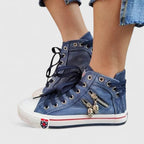 Navy blue denim high-top sneakers with lace-up front and metal charm detail on the side